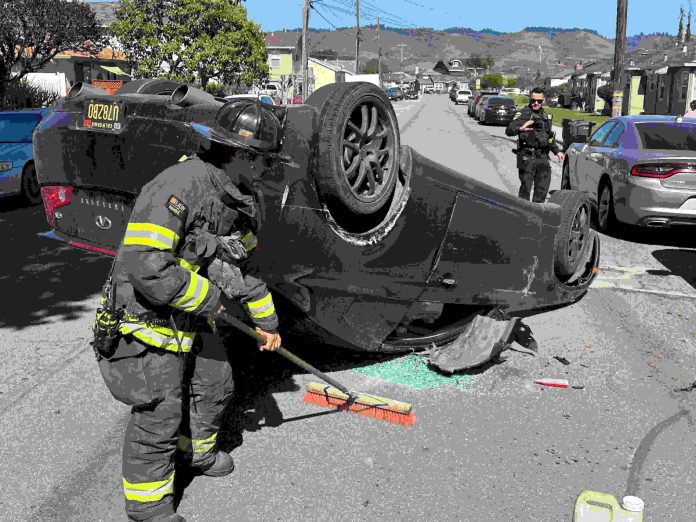 A Watsonville firefighter cleans up at the scene of a two-vehicle crash Tuesday afternoon on Center Street in Watsonville.