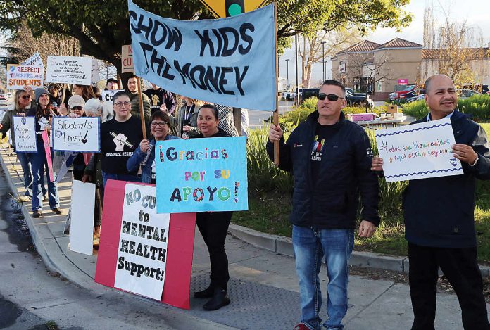 Pajaro Valley Unified School District teachers and staff are joined by community supporters early Tuesday morning at The Towers in Watsonville to rally against teacher layoffs.