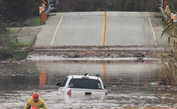 A State Parks Rescue swimmer paddles to shore from a pickup that stalled in flood water on Paulsen Road in 2023. New funding could help prevent this annual event.