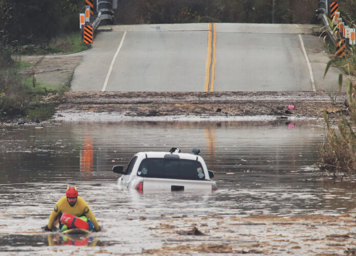 A State Parks Rescue swimmer paddles to shore from a pickup that stalled in flood water on Paulsen Road in 2023. New funding could help prevent this annual event.